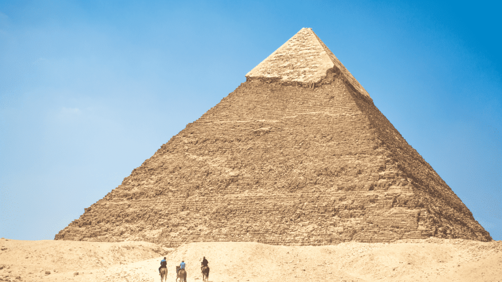 People Riding A Camel Near Pyramid Under Blue Sky - Egypt