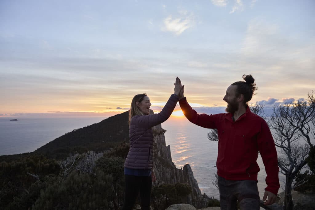 Tasmanian-Walking-Company-TWC-Three-Capes-Guided-Adventure-Walk-couple high five at the peak